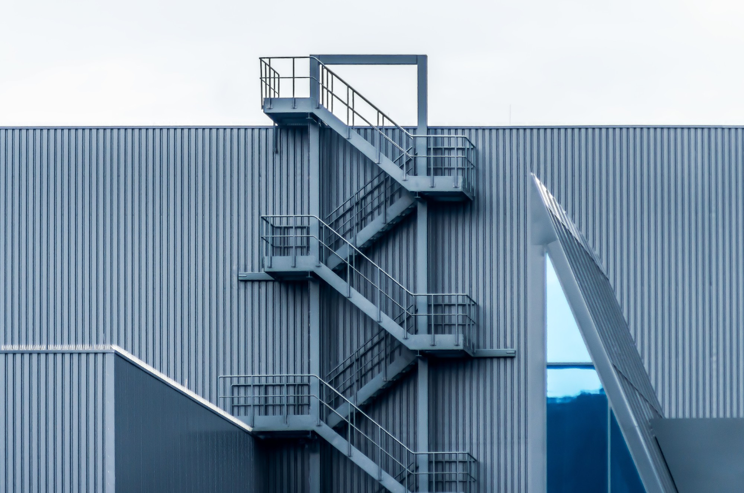 gray-metal-wall-with-spiral-stairs-clear-sky